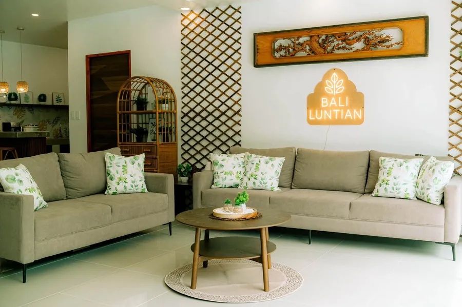 Living room sofas with leaf-print cushions under the lit Bhali Lhuntian sign