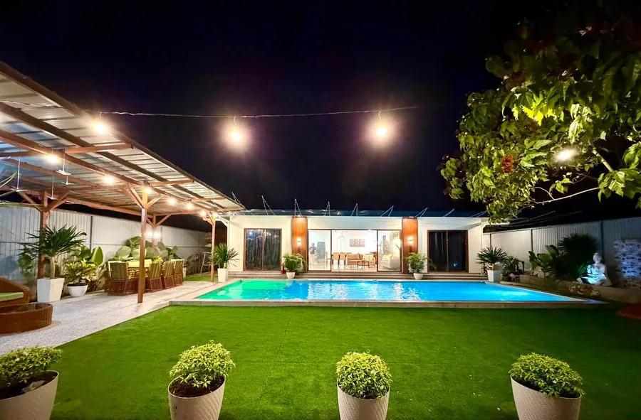 The lawn, pool and pavilion under evening lights