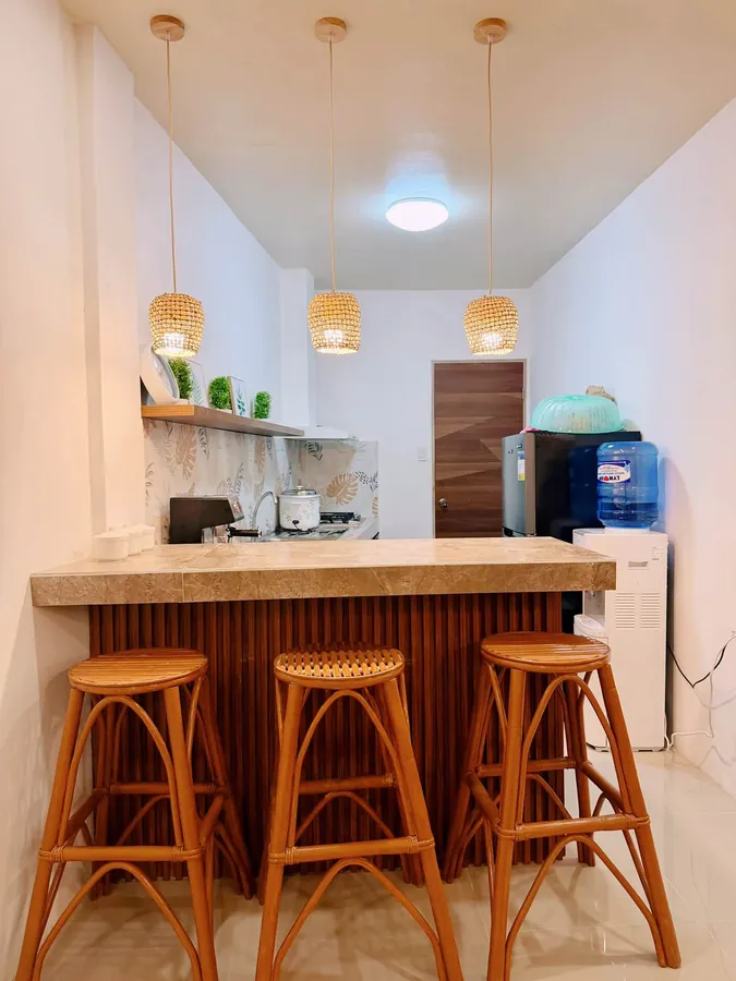 Kitchen bar with rattan stools, pendant lamps, refrigerator and water dispenser