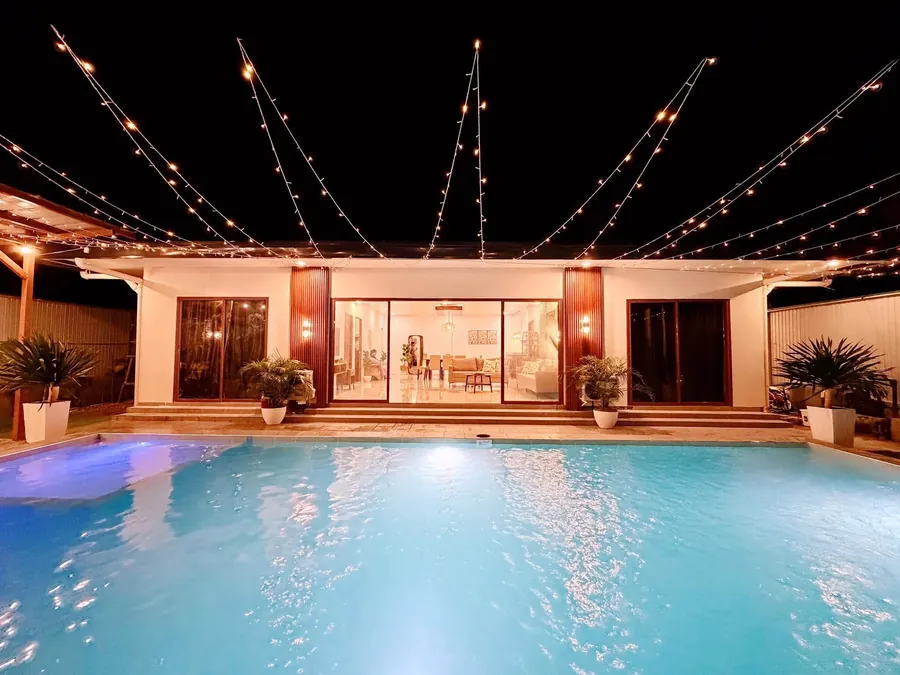 The pool in front of the villa at night under crossing string lights